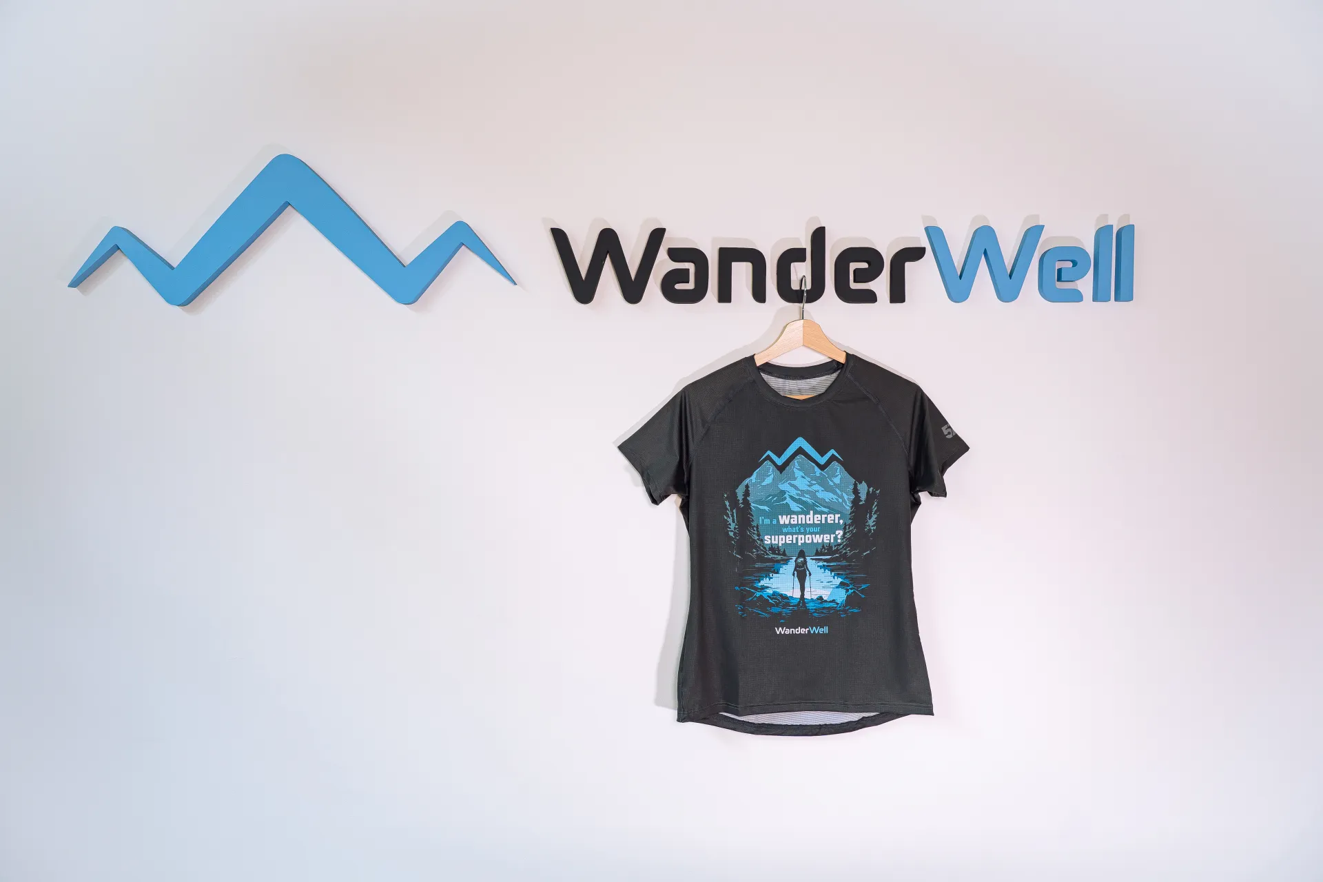 WanderWell törzsutas póló akasztón a WanderWell fali logó mellett