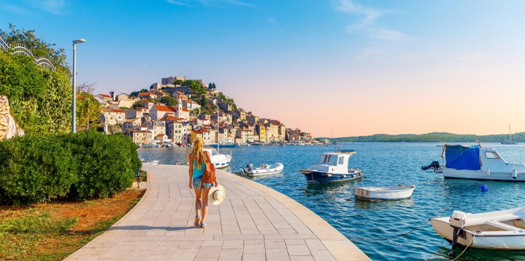 One,Person,Walking,Along,The,Sea,With,Boats,,Town,Of