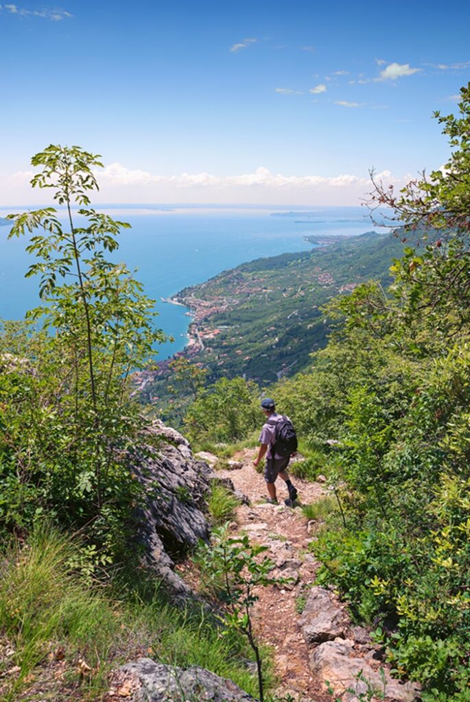 Backpacker,At,Idyllic,Hiking,Path,High,Above,Garda,Lake,With