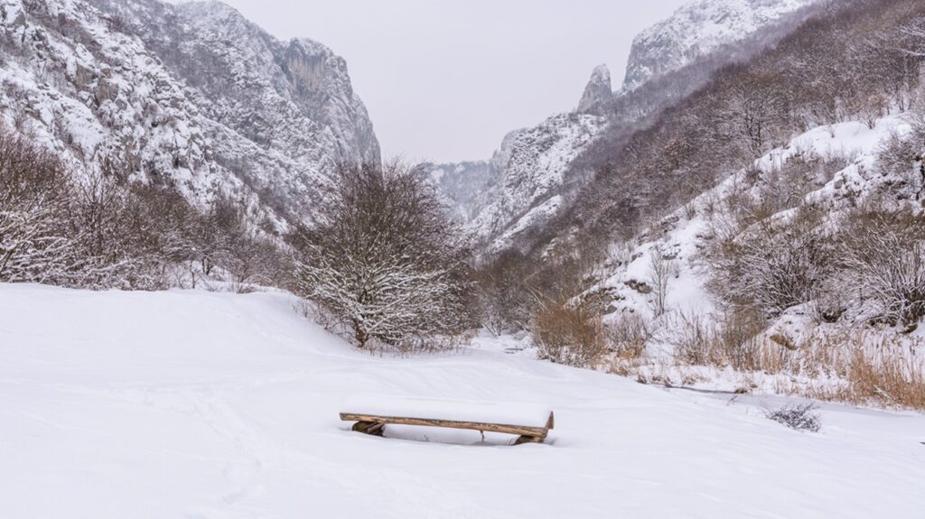 Lonely,Snow,Covered,Bench,And,Landscape,With,Rocky,Mountain,Gorge