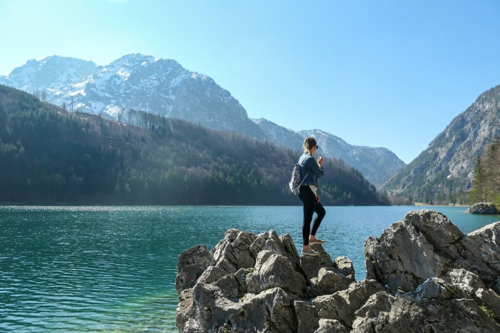 A,Woman,With,A,Backpack,Standing,On,A,Big,Stone